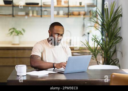 Young business black african american man working from home on table with notebook computer laptop Stock Photo