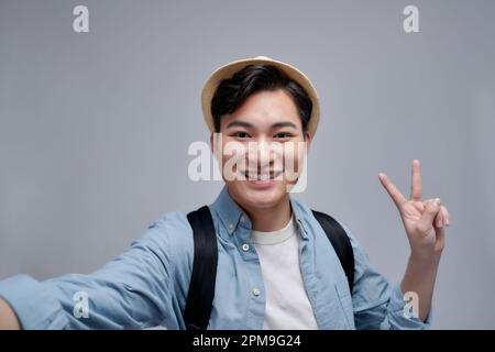 Self portrait of cheerfu blogger showing peace symbol with two fingers to the camera, making video for his blog Stock Photo