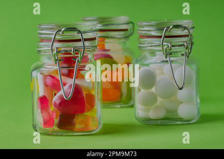 Jars of mixed sweets on a green background. Stock Photo