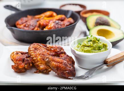 Grilled chicken legs and wings with guacamole, frish salad and spicies Stock Photo