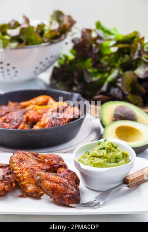 Grilled chicken legs and wings with guacamole, frish salad and spicies Stock Photo