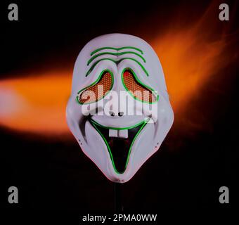 Scary mask with flames behind it on a black background. Stock Photo