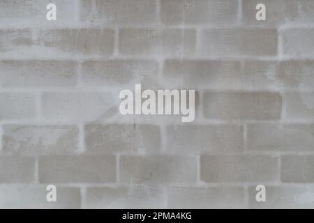 Brick block wall background with plaster and reinforcing mesh for wall plastering. Piece of brick wall under plaster. White gray stucco and brick wall Stock Photo