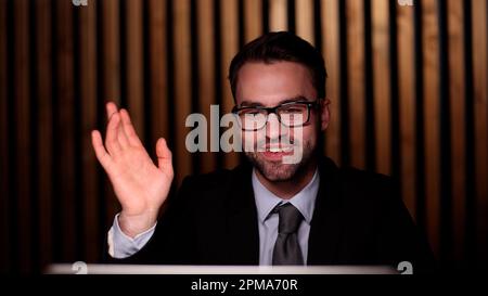 Young successful businessman waving his hand, greeting a colleague. Stock Photo
