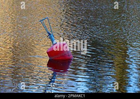 A red buoy floats on the surface of the lake Stock Photo