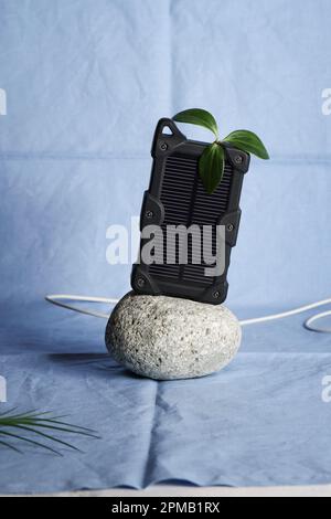 cheapest source of electricity. power box, portable solar battery for phone on stone on blue background. innovative solutions concept. copy space  Stock Photo