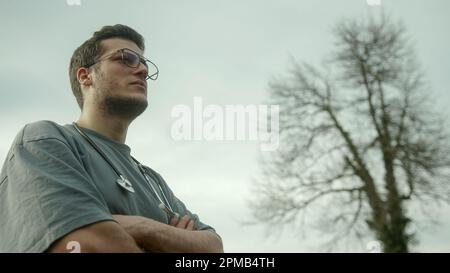 Long-Tall Handsome Glasses Doctor with Crossed Arms and Stethoscope Looking into the Landscape Stock Photo
