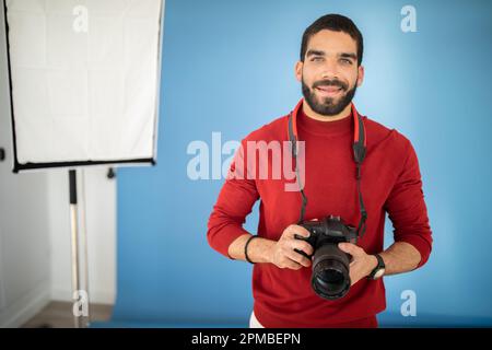 Happy handsome young guy professional photographer using digital camera Stock Photo