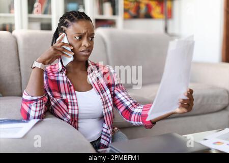 Irritated black woman entrepreneur checking papers, have phone call Stock Photo