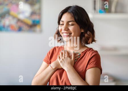 Gratitude Concept. Thankful Arab Woman With Both Palms On Chest Standing Indoors Stock Photo