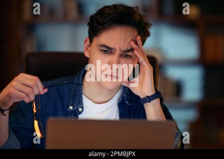 Closeup of concerned guy freelancer looking at laptop screen Stock Photo