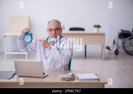 Old doctor in time management concept Stock Photo