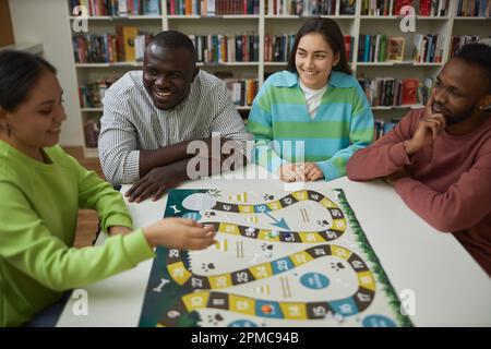 Diverse group of friends playing board game together at table and having fun, copy space Stock Photo