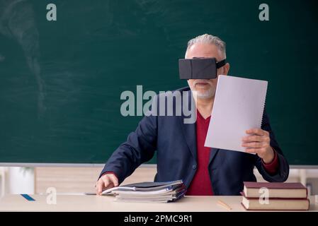 Old teacher wearing virtual glasses in the classroom Stock Photo