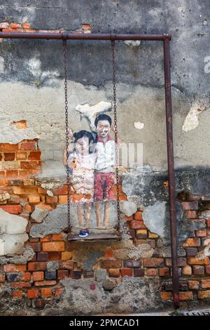 Street Art mural brother and sister on a swing kids on a wall portrait format in George Town on Penang island in Malaysia Stock Photo