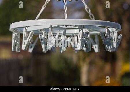 Plastic rotary dryer with attached clothes pegs with soft-focused garden in the background Stock Photo