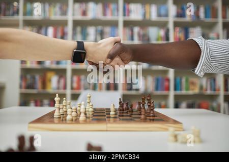 Side view close up of two chess players shaking hands over chess board after match Stock Photo