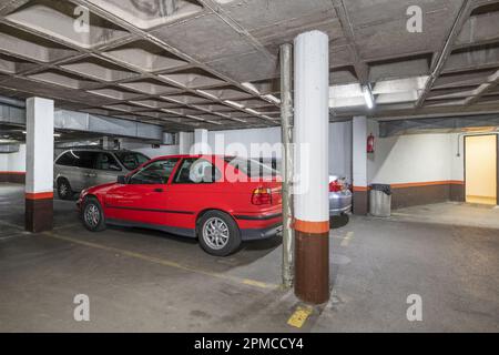 A few utility vehicles parked in the parking spaces of a residential building Stock Photo