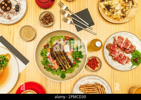 Set of healthy food dishes, desserts and toasts for brunch on a light pine wood table Stock Photo