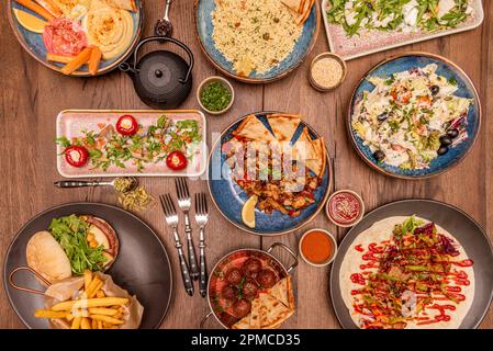 Set of colorful muby healthy food plates with cane meatballs, salad, tomatoes, hummus of various flavors on wooden table Stock Photo