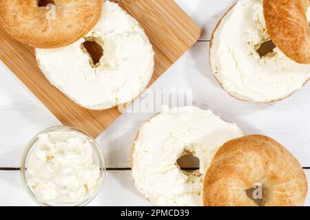 Bagel sandwich with fresh cream cheese for breakfast from above on a wooden board Stock Photo
