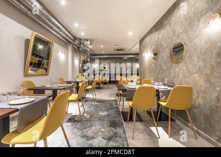 Dining room of a restaurant with assembled tables and chairs upholstered in yellow fabric Stock Photo