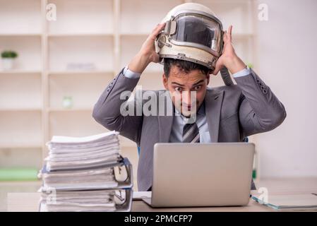 Young businessman employee wearing spacesuit at workplace Stock Photo