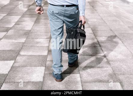 Businessman in a light-colored suit and dark briefcase going to work, back view Stock Photo
