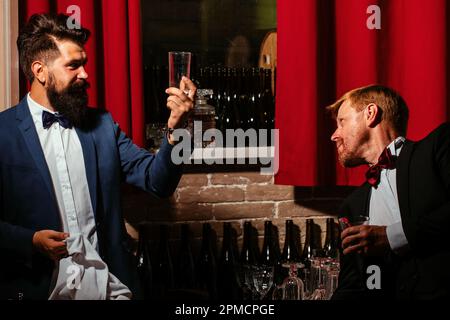 Barmen and customer. Alcohol beverage. Barman at counter. Hipster in bar. Old traditional whiskey drink. Gentlemans beverage. Stock Photo