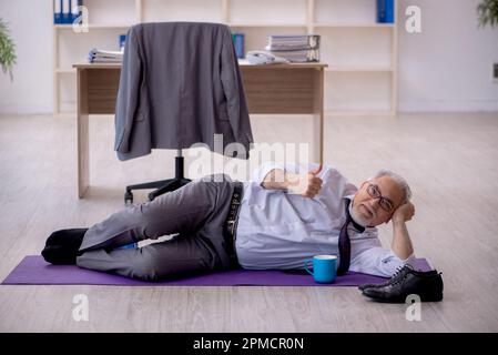 Old employee doing sport exercises during break Stock Photo