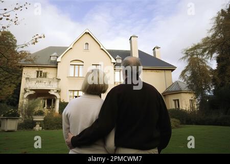 wealthy couple standing in front of a home Stock Photo