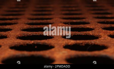 Rusty perforated metal plate with circular holes in shallow focus – industrial texture and decay concept. Stock Photo