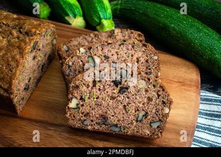 Slices of Freshly Baked Homemade Zucchini Bread: Sliced zucchini bread on a wood cutting board with fresh zucchini Stock Photo