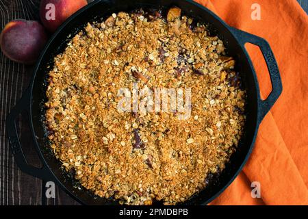 Freshly Baked Bourbon Pecan Peach Crisp Topped with Vanilla Ice Cream: Dessert made with peaches, bourbon, and pecans in a cast iron skillet Stock Photo