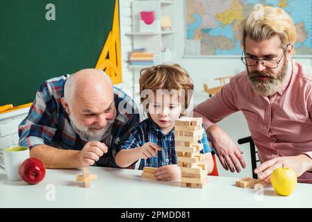 Jenga game at home. Happy generational muti three generation men family portrait. Man in different ages. Stock Photo