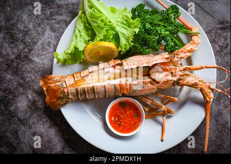 spiny lobster food on plate, fresh lobster or rock lobster seafood with herb and spices lemon coriander parsley lettuce salad, lobster for cooking foo Stock Photo
