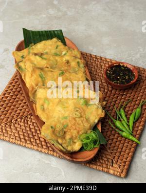 Tempe Mendoan, Deep Fried Thin Sliced Tempeh Covered in Flour Batter with a Mixture of Green Onion and Spices. Served with Spicy Sweet Sou Sauce and G Stock Photo