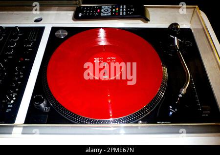 turntable closeup. red 45 speed LP record. silver metal finish. music and disc jockey concept. old style black vinyl disc. analog stereo technology. Stock Photo