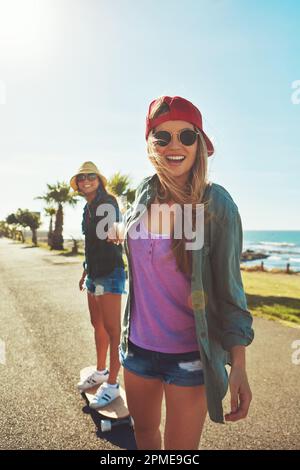 Rolling down the waterfront. two friends hanging out on the boardwalk with a skateboard. Stock Photo