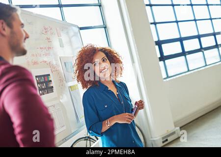 Collaborating is their key to success. designers brainstorming on a whiteboard in an office. Stock Photo