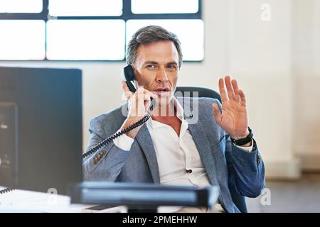 No excuses, just get it done. a mature businessman making a serious call on the phone at work. Stock Photo