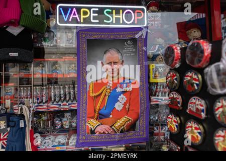 Souvenir shop in London selling King Charles III Coronation tea towel, advertised under the Vape Shop sign in a high street shop window, London, UK Stock Photo