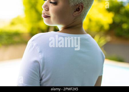 Close up of biracial woman wearing white tshirt over swimming pool in garden Stock Photo