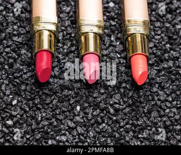 Different colors of lipstick on anthracite surface with copy space. Close-up, selective focus Stock Photo