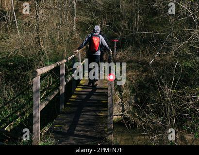 Two hikers walking over an old loose bridge on a marked hiking path in Slovenia leading up to kislica hill following spicasti vrh. Stock Photo