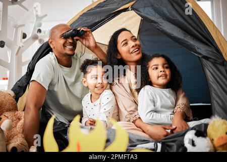 Family, living room and tent with kids, games and toys for bonding, love and playing together. Parents, girl children and looking with mom, dad or Stock Photo