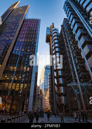 Workers head home in London's financial district. Towering overhead are the iconic "Inside Out" Lloyds of London, The Scalpel & The Walkie Talkie Stock Photo