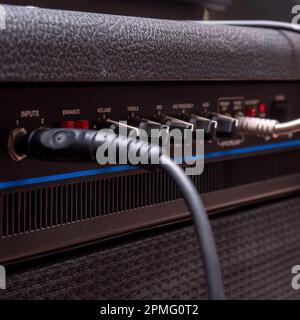 Plug jack with cable plugged into a black guitar combo amplifier Stock Photo