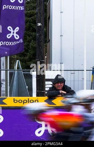 Overijse, Belgium. April 12, 2023.  Illustration picture shows a spectator watching the front group pass for the last round in Overijse near the finish line. Picture shows a Proximus flag and Boplan boarding @ the BRABANTSE PIJL women cycling race, 141,2 km from LENNIK to OVERIJSE, Wednesday April 12th 2023. PHOTO SPORTPIX | Thijs Wintein Stock Photo