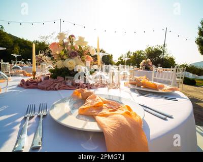 Beautiful outdoor wedding decoration in city. Candles and dried flowers and accessories with bouquets and glasses on table with linen tablecloth on Stock Photo